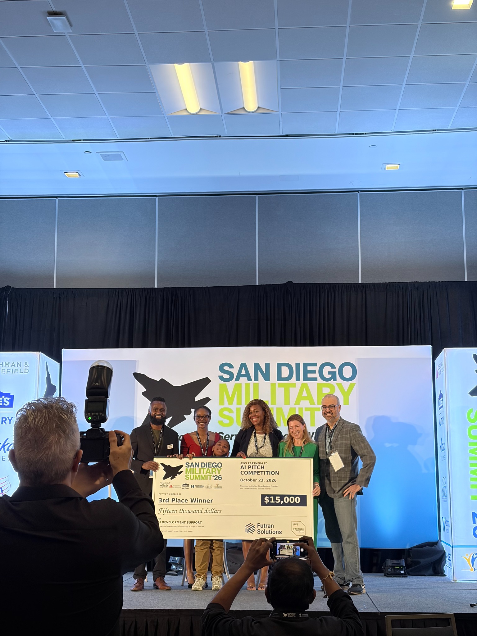 LaShea with a group at the award presentation holding the San Diego Military Summit third place $15,000 AI development support check